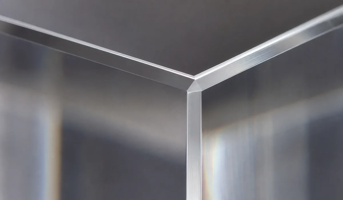 Macro close-up of a diamond-polished cast acrylic photo block edge, light catching the crisp 90-degree corner of the glossy PMMA face