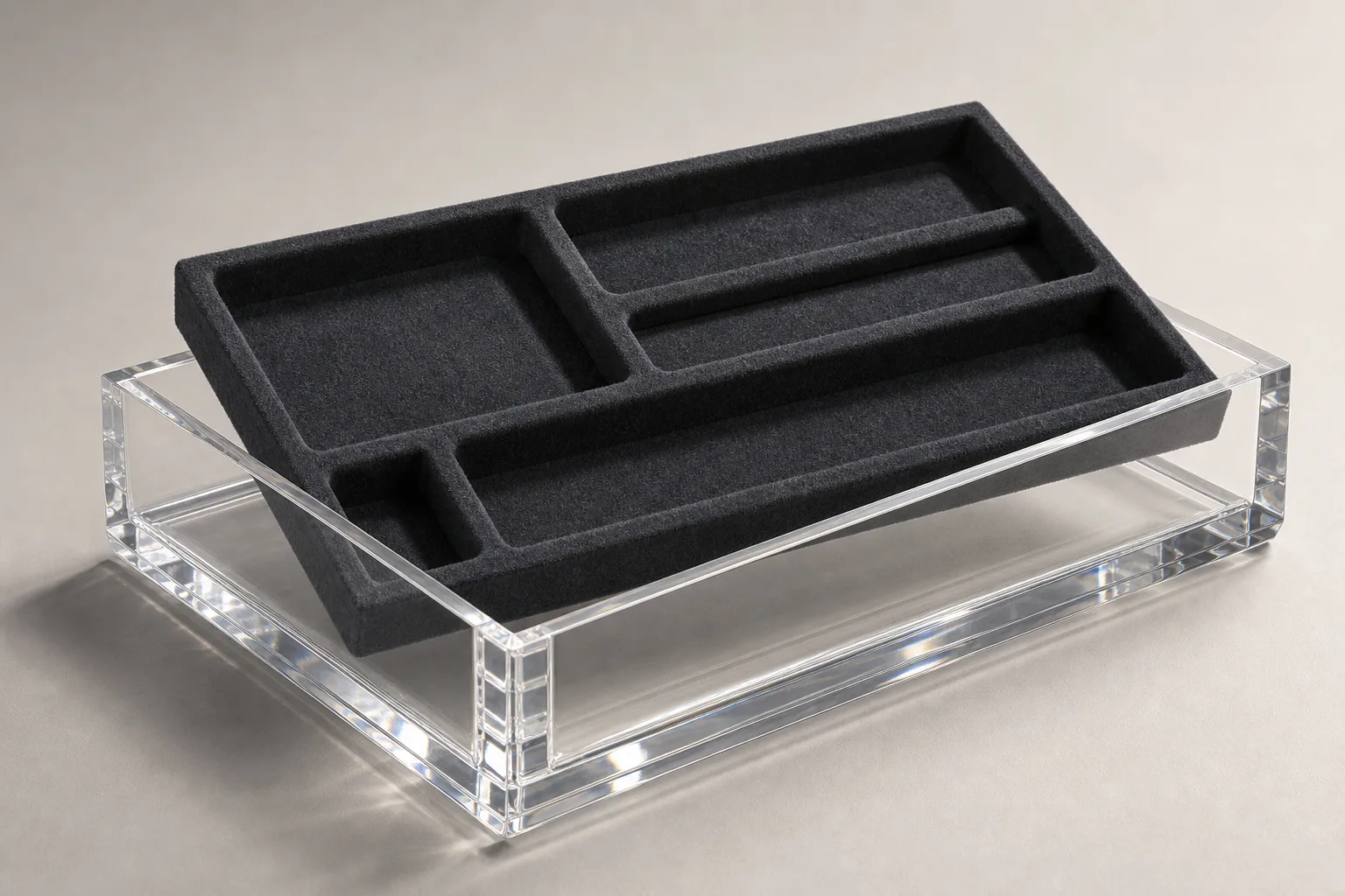 Clear acrylic tray with a removable charcoal felt-lined insert lifted partway out, showing die-cut compartments and the polished PMMA tray wall refracting light
