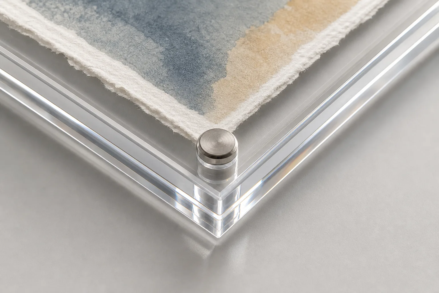Close-up of an acrylic floating frame corner — two clear PMMA panels clamping a deckle-edged art print, corner magnet visible, polished acrylic edges refracting light
