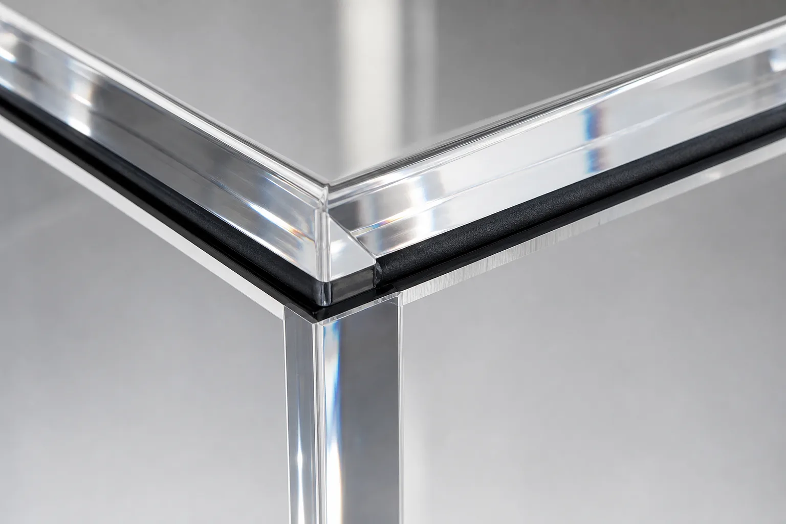 Corner detail of a museum-grade acrylic display case showing a black gasket line compressed between the clear PMMA hood and its base, with a polished mitered edge refracting light