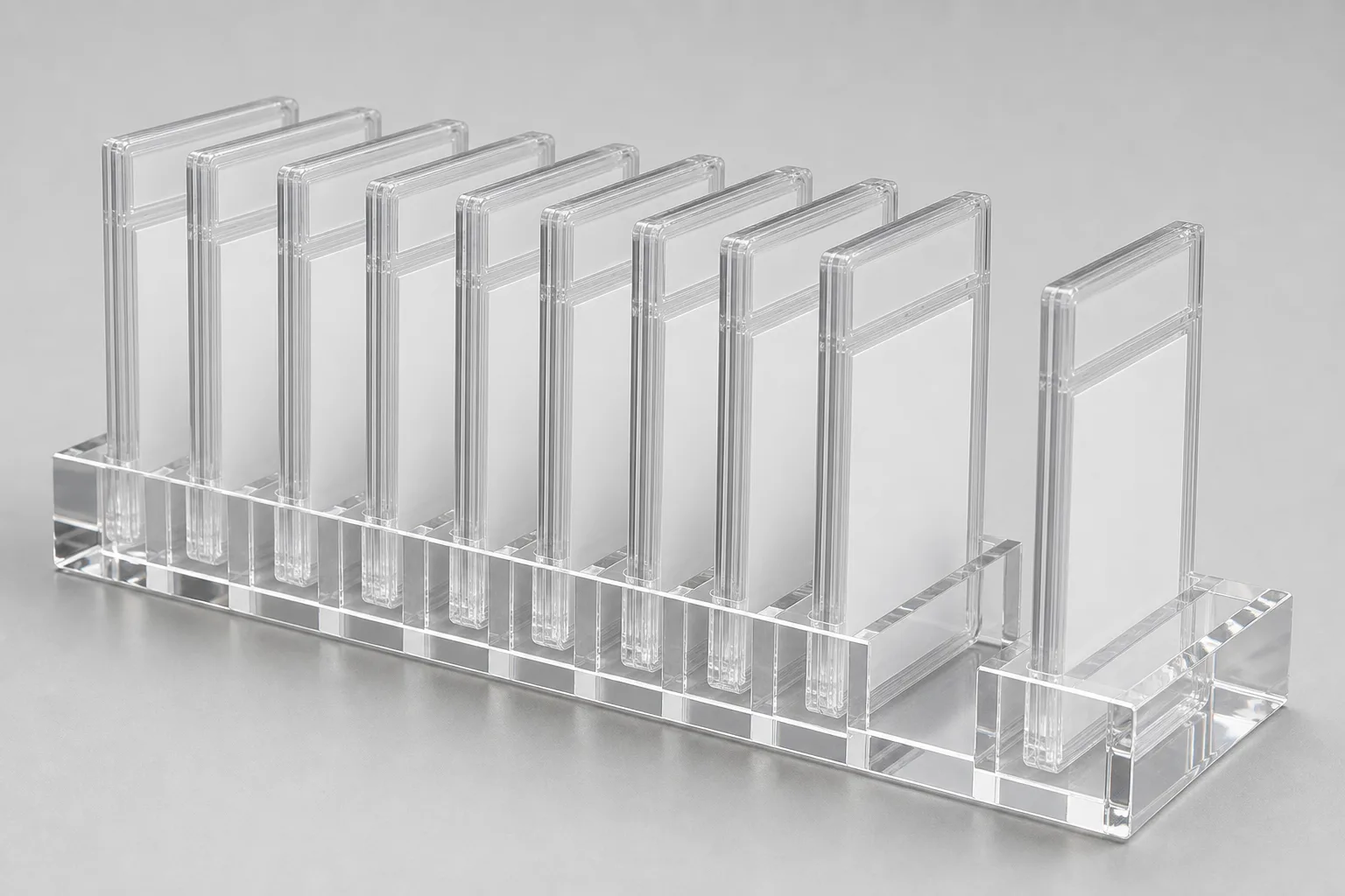 Clear acrylic multi-slot display block holding a row of encapsulated PSA graded card slabs at uniform spacing, with one empty slot showing the precision-cut channel width