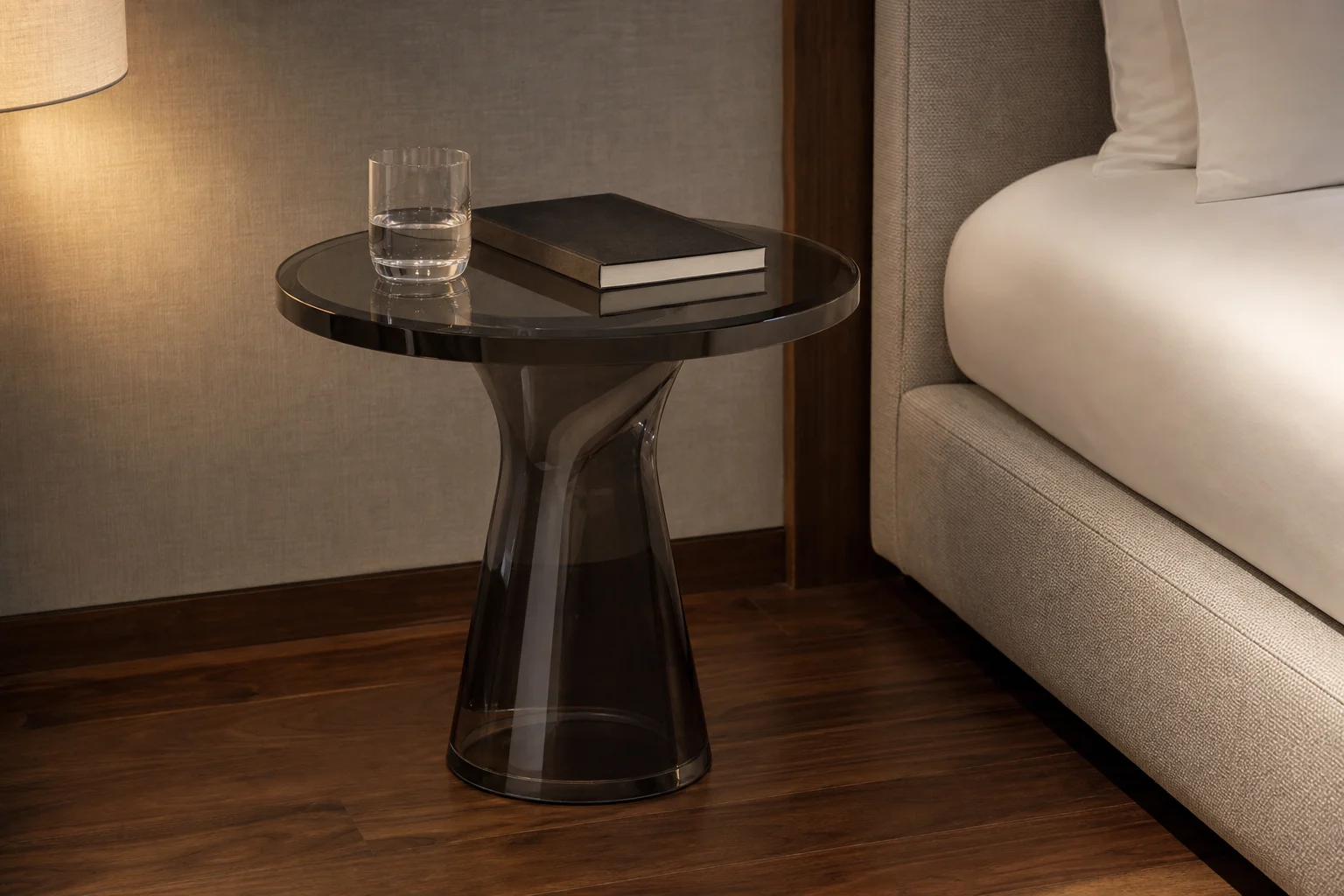 Single clear cast acrylic round side table on a sculptural pedestal base, polished mirror-clear surface in a boutique hotel suite