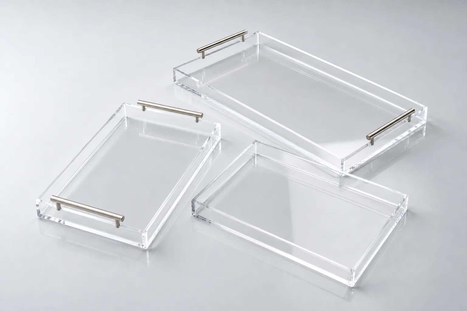 Custom acrylic serving trays in metal-handle, cut-out-handle, and handleless styles on a clean light-gray background