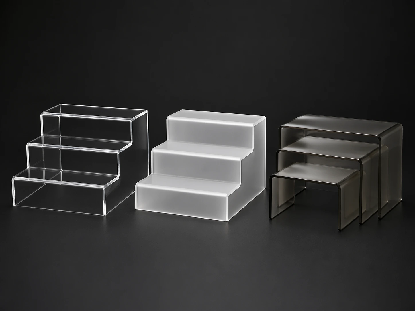 Collection of custom acrylic risers in clear, frosted, and smoke-gray acrylic for retail display
